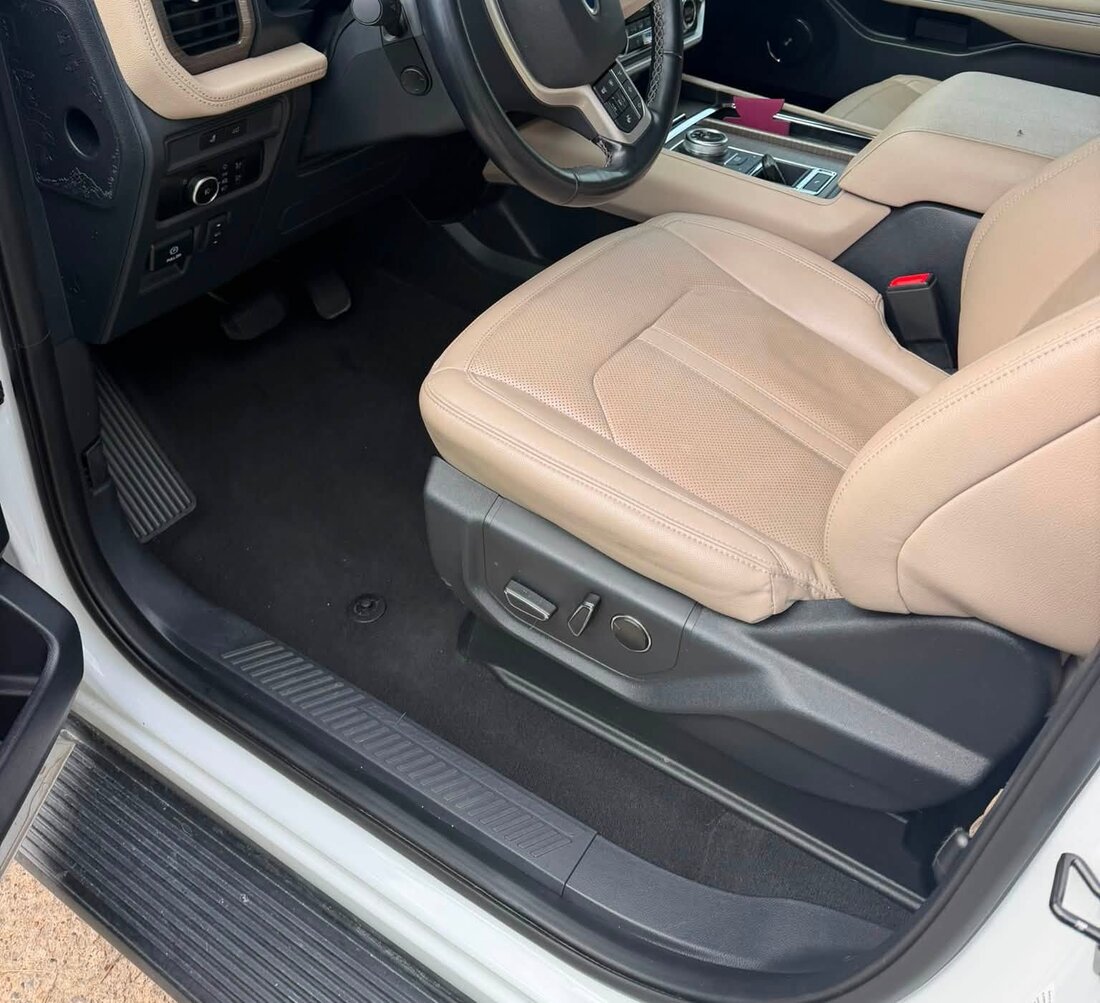 The same SUV footwell after a full interior detail, with clean carpet and tan leather
