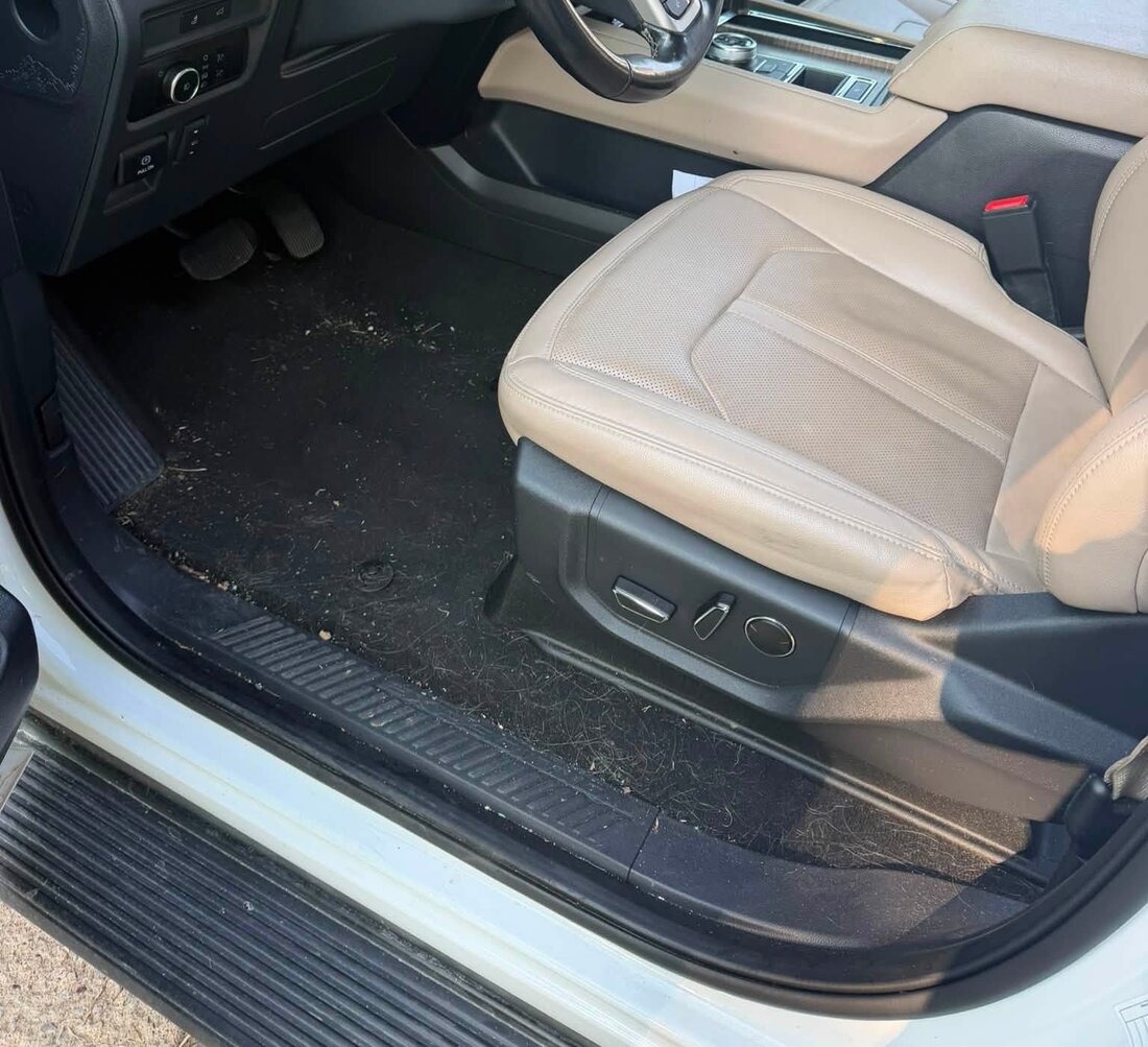 SUV driver footwell before cleaning, covered in dirt, grass and debris