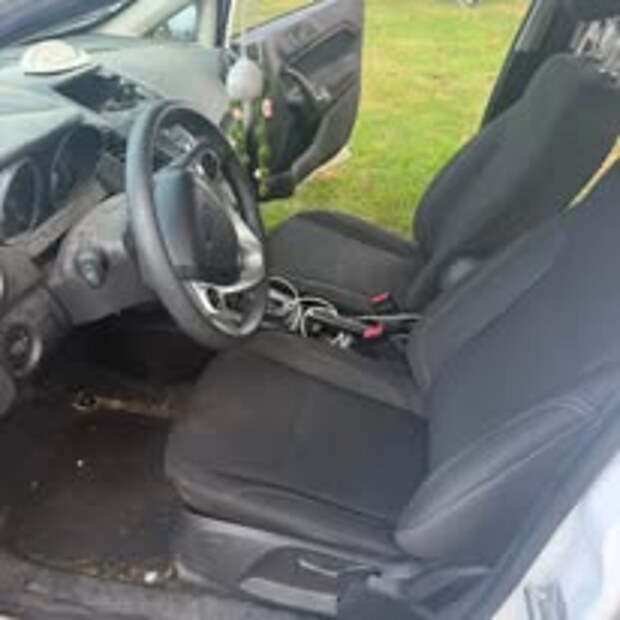 Ford Fiesta front seats and floor with leaves and debris before cleaning